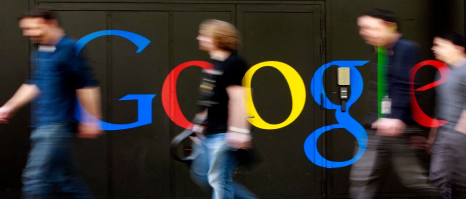 People walk past a logo next to the main entrance of the Google building in Zurich