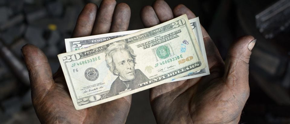 Worker hands covered with oil holding money. Shutterstock