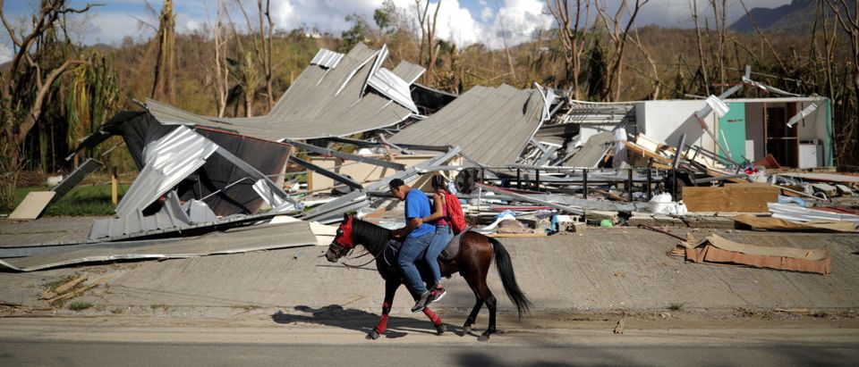 Local residents ride a horse by a destroyed building after Hurricane Maria in Jayuya, Puerto Rico