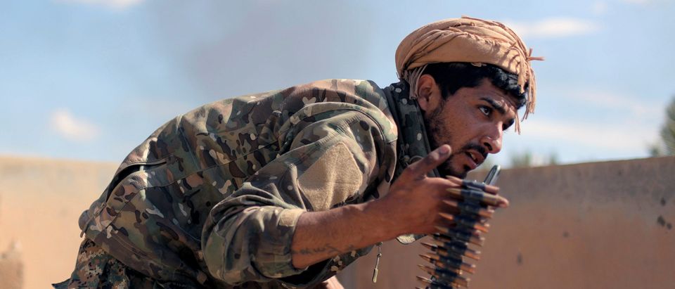 A fighter of Syrian Democratic Forces (SDF) carries ammunition in Baghouz, Deir Al Zor province