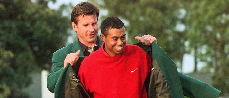 Tiger Woods (R) receives the Masters green jacket