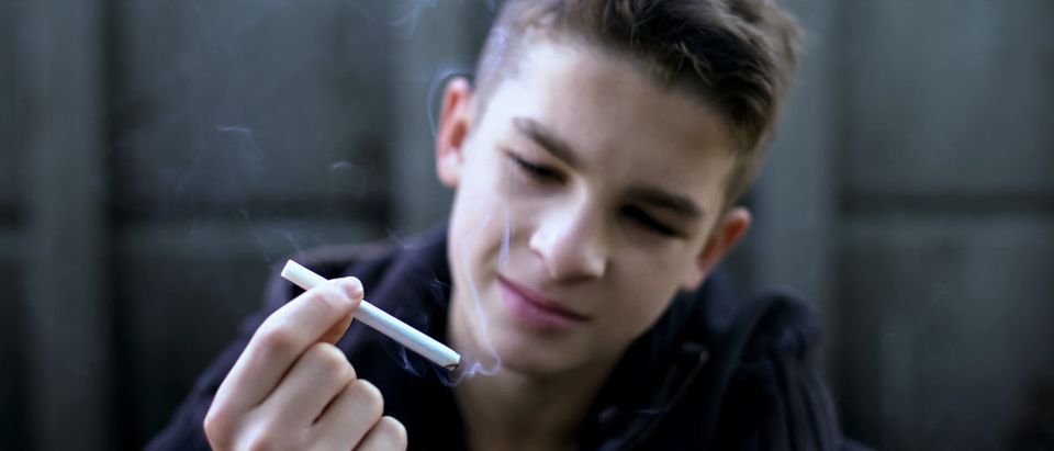 A boy holds a cigarette. Shutterstock image via user Motortion Studio