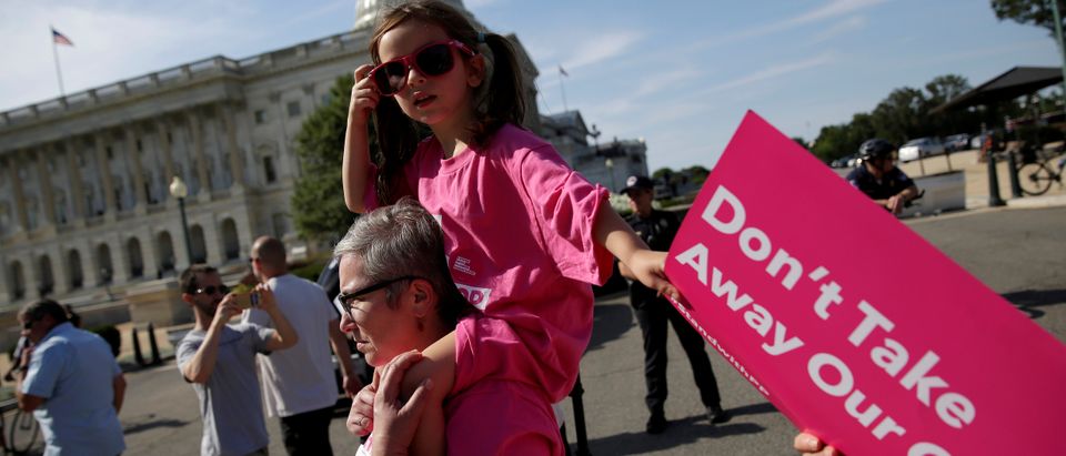 A girl is carried as healthcare activists with Planned Parenthood and the Center for American Progress protest in opposition to the Senate Republican healthcare bill on Capitol Hill in Washington, U.S., June 28, 2017. REUTERS/Joshua Roberts