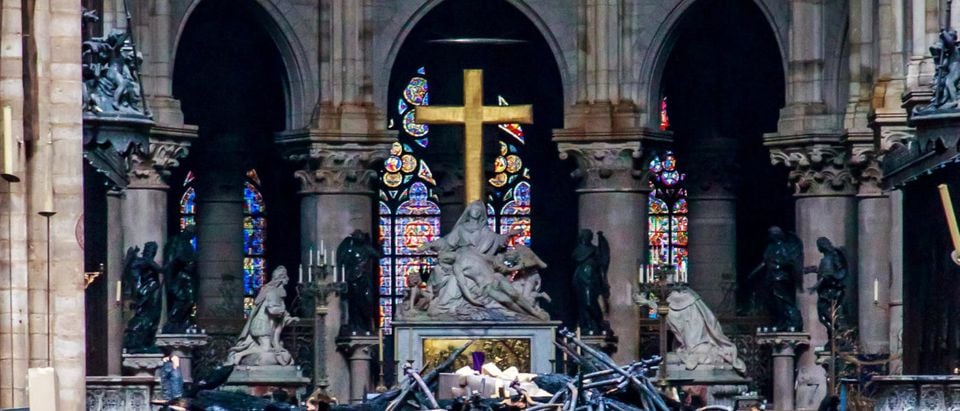 A view of the cross and sculpture of Pieta by Nicolas Coustou in the background of debris inside Notre-Dame de Paris, in the aftermath of a fire that devastated the cathedral, during the visit of French Interior Minister Christophe Castaner (not pictured) in Paris, France, April 16, 2019. Christophe Petit Tesson/Pool via REUTERS