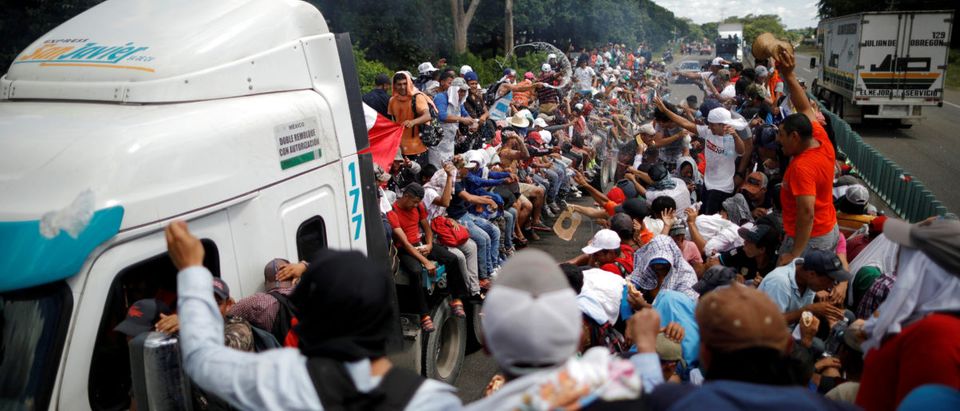 A caravan of migrants trying to reach the United States hitchhike on a truck along the highway in Tapachula
