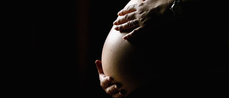 A pregnant woman holds her stomach June 7, 2006 in Sydney, Australia. (Photo by Ian Waldie/Getty Images)