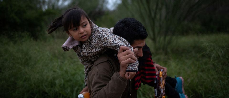 Jose Moreira Deras of Honduras races down a dirt path holding his five year old daughter Crystal after hearing what border patrol agents said was the sound of gunshots where a group of two dozen families members illegally crossed the Rio Grande river into the United States from Mexico, in Fronton, Texas, Oct. 18, 2018. REUTERS/Adrees Latif