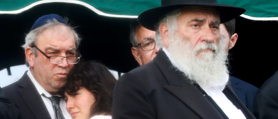 SAN DIEGO, CALIFORNIA - APRIL 29: Hannah Kaye (2nd L), daughter of shooting victim Lori Gilbert Kaye, is comforted as she mourns, while Rabbi Yisroel Goldstein (R) who was wounded by the shooter walks past during a graveside service on April 29, 2019 in San Diego, California. Lori Gilbert Kaye was killed inside the Chabad of Poway synagogue on April 27 by a gunman who opened fire as worshippers attended services. (Photo by Mario Tama/Getty Images)
