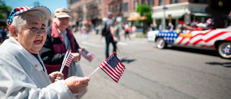 An elderly woman waves American flags to veterans as they march on the street May 27, 2019 during the 152nd Memorial Day Parade in the New York City borough of Brooklyn. (JOHANNES EISELE/AFP/Getty Images)