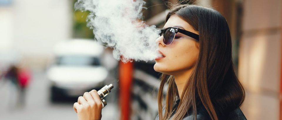 A woman smokes an e-cigarette. Shutterstock image via Oleggg