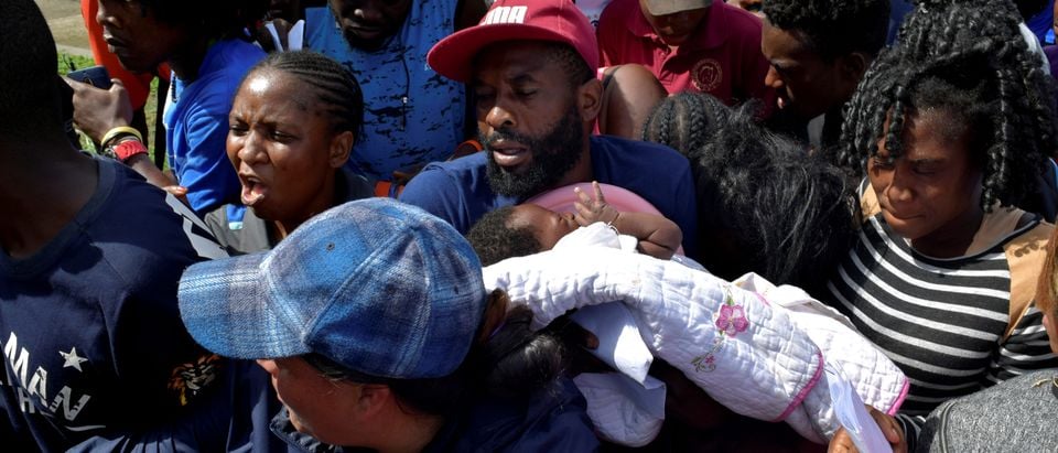 FILE PHOTO: A migrant from Cameroon holds his baby while trying to enter the Siglo XXI immigrant detention center to request humanitarian visas, issued by the Mexican government, to cross the country towards the United States, in Tapachula, Mexico June 27, 2019. REUTERS/Jose Torres