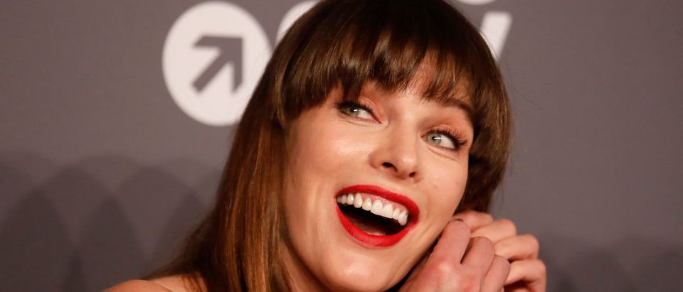 Milla Jovovich puts on her earring on the red carpet for the amfAR gala in New York, U.S., February 6, 2019. REUTERS/Shannon Stapleton