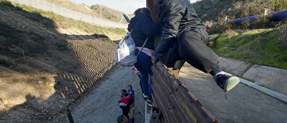 Honduran migrants climb over a border fence in Tijuana, Mexico on January 6, 2019. (Sandy Huffaker/Getty Images)