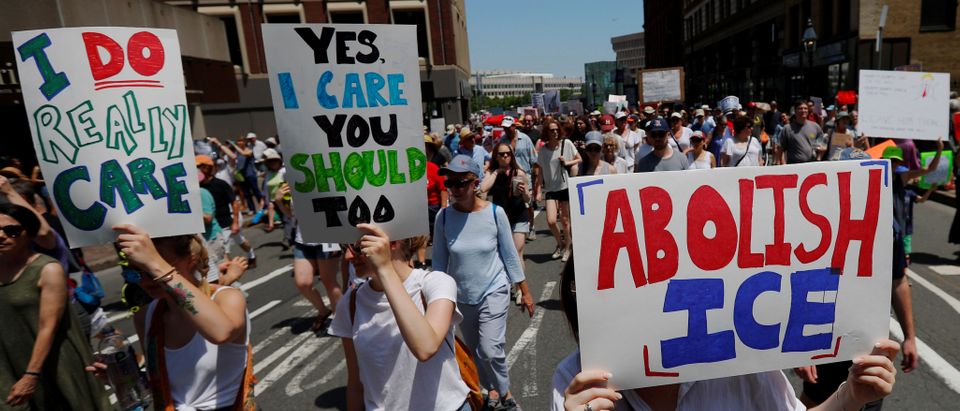 Demonstrators carrying signs reading "Abolish ICE" and "I Really Do Care", referencing the coat recently worn by First Lady Melania Trump, march during the "Families Belong Together" rally in Boston