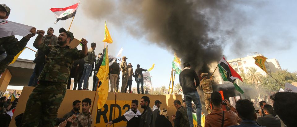 Members of the Iraqi pro-Iranian Hashed al-Shaabi group and protesters set ablaze a sentry box in front of the US embassy building in the capital Baghdad to protest against the weekend's air strikes by US planes on several bases belonging to the Hezbollah brigades. (AHMAD AL-RUBAYE/AFP via Getty Images)