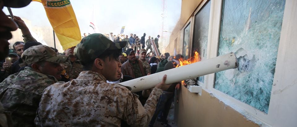 Iraqi protesters use a plumbing pipe to break the bullet-proof glass of the US embassy's windows in Baghdad, as thousands of angry Iraqis, including members the Hashed al-Shaabi breached the outer wall of the diplomatic mission on December 31, 2019. (AHMAD AL-RUBAYE/AFP via Getty Images)