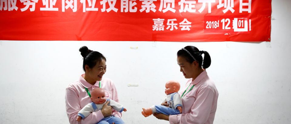 Students at Ayi University, a training program for domestic helpers, practice on baby dolls during a course teaching childcare in Beijing, China, Dec. 5, 2018. REUTERS/Thomas Peter