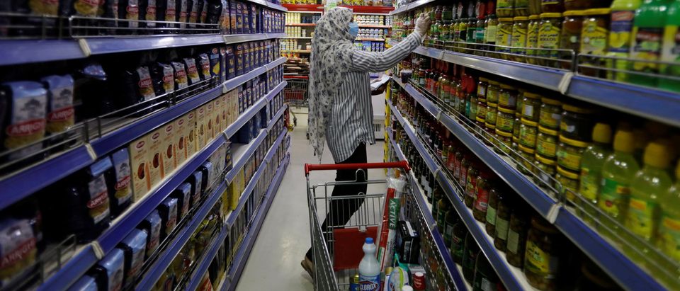 A woman wears a protective face mask and gloves, as she shops at a supermarket before curfew, following the outbreak of coronavirus, in Baghdad