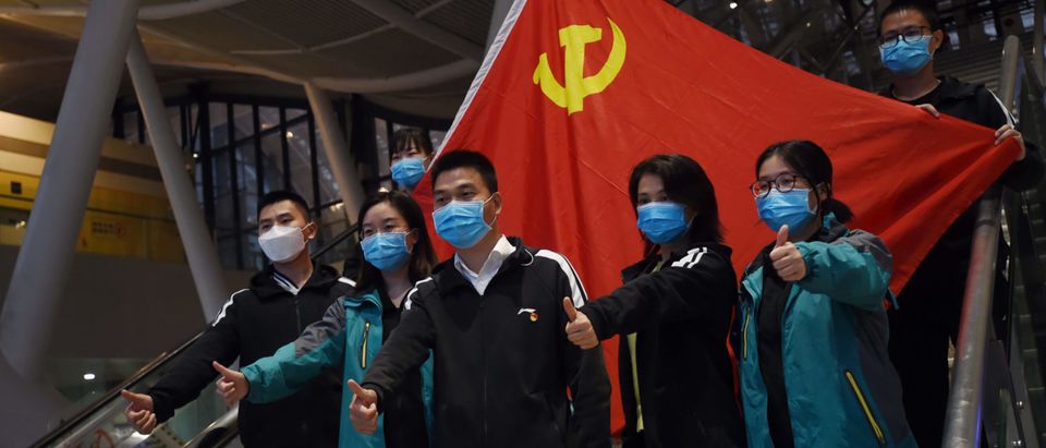 Medical workers from outside Wuhan pose for pictures with a Chinese Communist Party flag at the Wuhan Railway Station before leaving the epicentre of the novel coronavirus disease outbreak