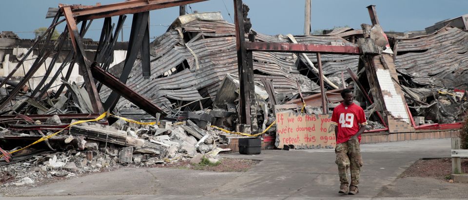 MINNEAPOLIS, MINNESOTA - JUNE 02: A man walk past the charred wreckage of a building destroyed during last week's rioting which was sparked by the death of George Floyd on June 2, 2020 in Minneapolis, Minnesota. Floyd was killed on May 25 while in Minneapolis police custody. Officer Derek Chauvin has been fired from the force, arrested and charged with third degree murder. (Photo by Scott Olson/Getty Images)