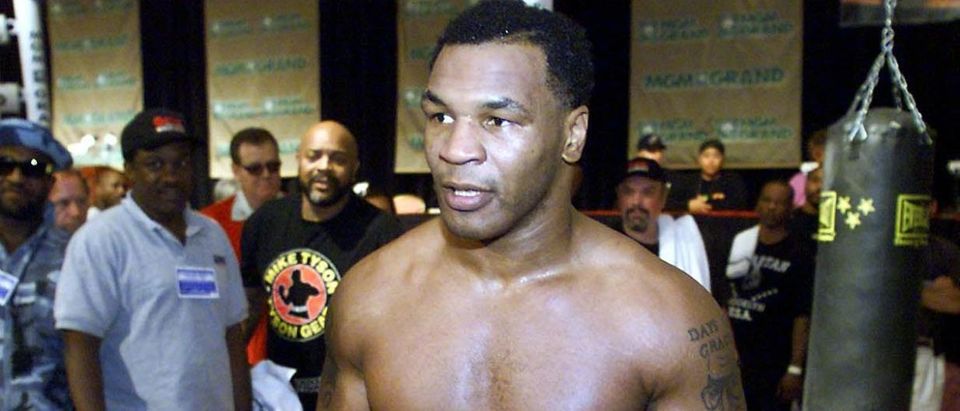 Former world heavyweight boxing champion Mike Tyson (C) sheds his shirt before the media following his workout 19 October 1999 at the MGM Grand Hotel in Las Vegas, NV. Tyson will return to the ring 23 October 1999 to fight Orlin Noris, of Lubbock, Texas. (Photo credit JOHN GURZINSKI/AFP via Getty Images)