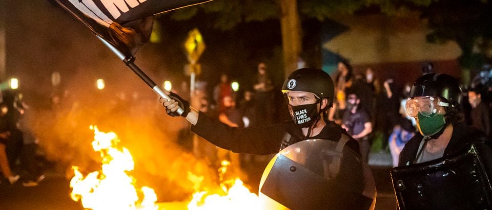 PORTLAND OR - SEPTEMBER 6: Protesters gather in front of a fire near the North police precinct during a protest against racial injustice and police brutality on September 6, 2020 in Portland, Oregon. Sunday marked the 101st consecutive night of protests in Portland. (Nathan Howard/Getty Images)