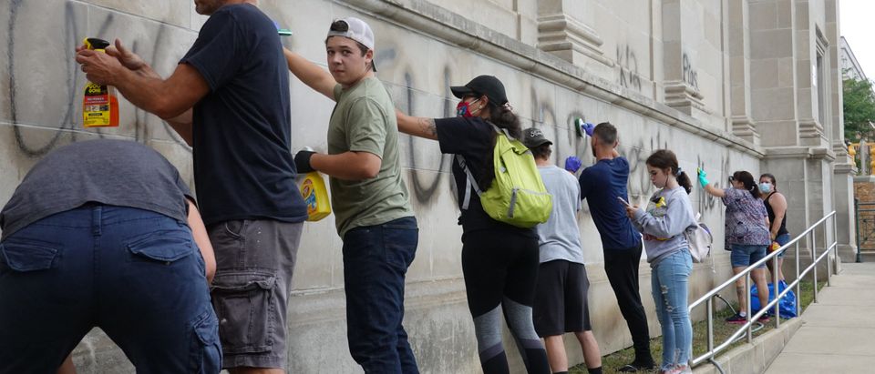 KENOSHA, WISCONSIN - AUGUST 25: Volunteers clean graffiti from a high school near the Kenosha County Courthouse following another night of unrest on August 25, 2020 in Kenosha, Wisconsin. Rioting as well as clashes between police and protesters began Sunday night after a police officer shot Jacob Blake, an unarmed Black man, seven times in the back in front of his three children. (Scott Olson/Getty Images)