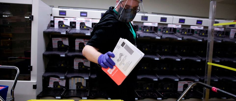 Election worker Gareth Fairchok removes ballots from a sorting machine as vote-by-mail ballots for the August 4 Washington state primary are processed at King County Elections in Renton, Washington on August 3, 2020. (Photo by Jason Redmond/AFP via Getty Images)