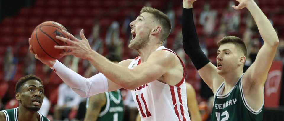 Dec 1, 2020; Madison, Wisconsin, USA; Wisconsin Badgers forward Micah Potter (11) makes a basket against Green Bay Phoenix forward Cem Kirciman (12) at the Kohl Center. Mandatory Credit: Mary Langenfeld-USA TODAY Sports via Reuters