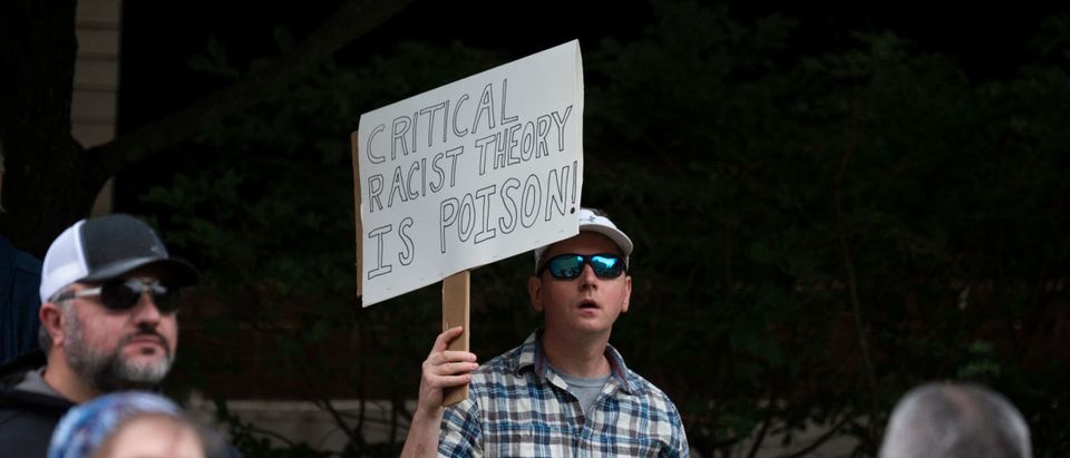 A man holds up a sign during a rally against "critical race theory" (CRT) being taught in schools at the Loudoun County Government center in Leesburg, Virginia on June 12, 2021. - "Are you ready to take back our schools?" Republican activist Patti Menders shouted at a rally opposing anti-racism teaching that critics like her say trains white children to see themselves as "oppressors." "Yes!", answered in unison the hundreds of demonstrators gathered this weekend near Washington to fight against "critical race theory," the latest battleground of America's ongoing culture wars. The term "critical race theory" defines a strand of thought that appeared in American law schools in the late 1970s and which looks at racism as a system, enabled by laws and institutions, rather than at the level of individual prejudices. But critics use it as a catch-all phrase that attacks teachers' efforts to confront dark episodes in American history, including slavery and segregation, as well as to tackle racist stereotypes. (Photo by Andrew Caballero-Reynolds/AFP via Getty Images)