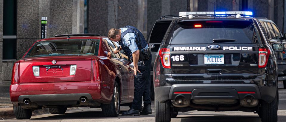 A Minneapolis Police officer checks a suspicious car without a plate parked near the Hennepin County Government Center. (Photo by KEREM YUCEL/AFP via Getty Images)