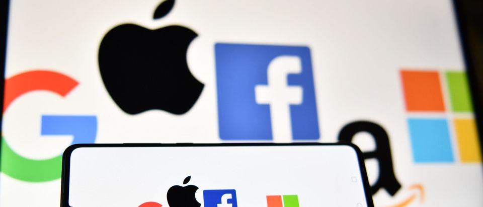 An illustration picture taken in London on December 18, 2020 shows the logos of Google, Apple, Facebook, Amazon and Microsoft displayed on a mobile phone and a laptop screen. (Photo by JUSTIN TALLIS/AFP via Getty Images)