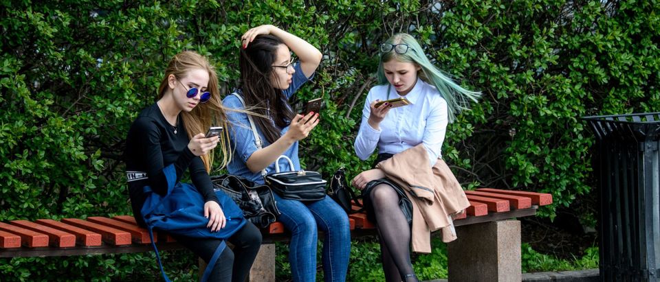 Girls use their smartphones while sitting on a bench in Yekaterinburg on May 24, 2018. (Photo credit should read MLADEN ANTONOV/AFP via Getty Images)