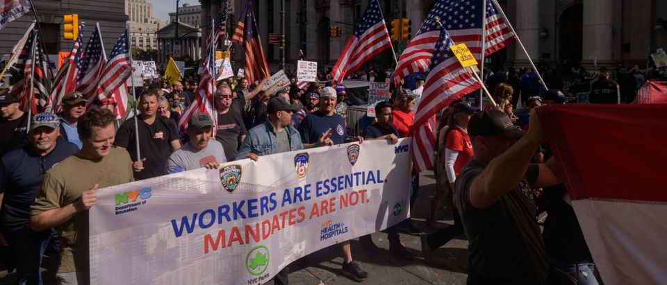Municipal workers hold placards and shout slogans as they march during a protest against the covid-19 vaccine mandate, in New York on October 25, 2021. - Several thousand New York City employees, mostly firefighters, two-fifths of whom are not vaccinated against Covid-19, marched on the Brooklyn Bridge to protest against the vaccine requirement announced last week by the town hall. (Photo by Ed JONES / AFP) (Photo by ED JONES/AFP via Getty Images)