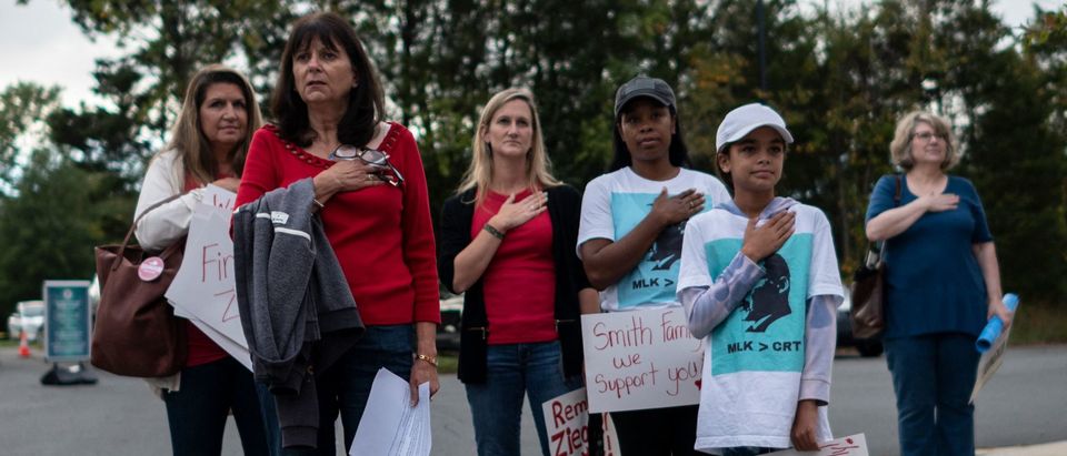 Protesters and activists stand at attention as the national anthem is sung to open a Loudoun County Public Schools (LCPS) board meeting in Ashburn, Virginia on October 12, 2021. (Photo by ANDREW CABALLERO-REYNOLDS/AFP via Getty Images)