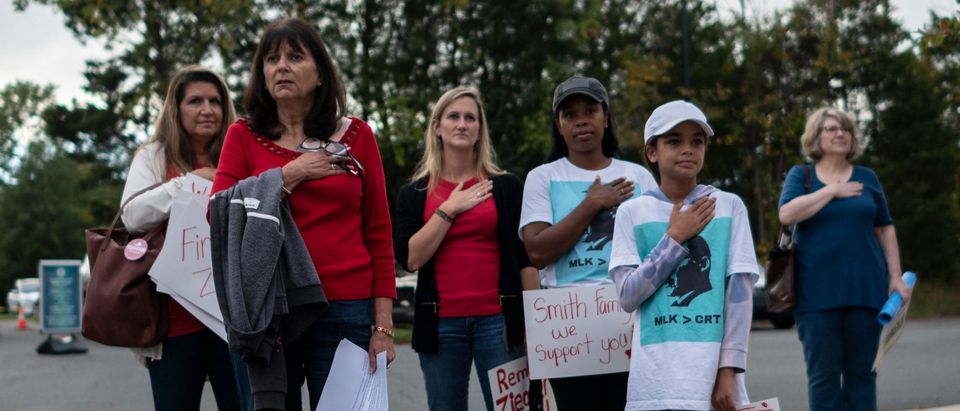 Protesters and activists stand at attention as the national anthem is sung to open a Loudoun County Public Schools (LCPS) board meeting in Ashburn, Virginia on October 12, 2021.(Photo by ANDREW CABALLERO-REYNOLDS/AFP via Getty Images)