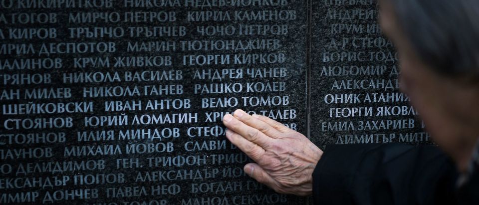 An elderly woman touches the name of her relative on the monument listing the victims of the communist regime during an open air mass in Sofia on February 1, 2020. - Bulgaria held commemorations for the victims of the country's 45-year communist regime at the anniversary of the first killings on February 1, 1945. Between December 1944 and April 1945, the self-proclaimed People's Court set up by the newly established communist regime ordered the killing of 2,730 Bulgarians. (Photo by NIKOLAY DOYCHINOV / AFP) (Photo by NIKOLAY DOYCHINOV/AFP via Getty Images)