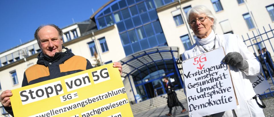 Andreas Kaufmann (L) and doctor Barbara Dohmen hold up posters declaring concerns on the 5G mobile standard to be harmful to health as they demonstrate in front of the German Federal Network Agency (BNA, Bundesnetzagentur) in Mainz, western Germany, prior to the start of Germany's auction for the construction of an ultra-fast 5G mobile network on March 19, 2019. - Germany launched the action as a transatlantic dispute rages over security concerns surrounding giant Chinese telecoms equipment maker Huawei. '5G' -- 'fifth generation' -- is the latest, high-speed generation of cellular mobile communications and Berlin will require winning bidders to offer 5G service to at least 98 percent of German households and along motorways and rail lines. (Photo by Arne Dedert / dpa / AFP) / Germany OUT (Photo credit should read ARNE DEDERT/DPA/AFP via Getty Images)