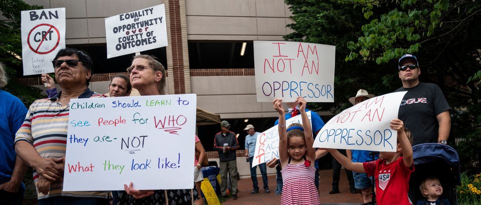 People hold up signs during a rally against "critical race theory" (CRT) being taught in schools at the Loudoun County Government center in Leesburg, Virginia on June 12, 2021. (Photo by ANDREW CABALLERO-REYNOLDS/AFP via Getty Images)