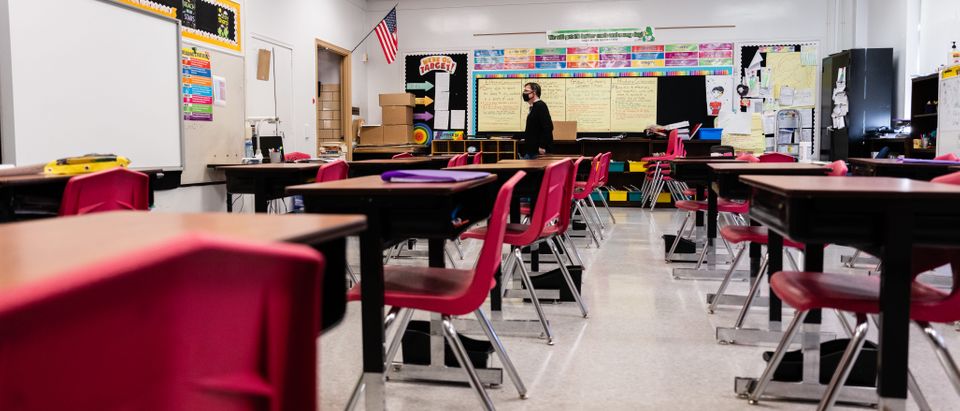 A teacher walks through an empty classroom during a period of Non-Traditional Instruction (NTI) at Hazelwood Elementary School on January 11, 2022 in Louisville, Kentucky. (Photo by Jon Cherry/Getty Images)