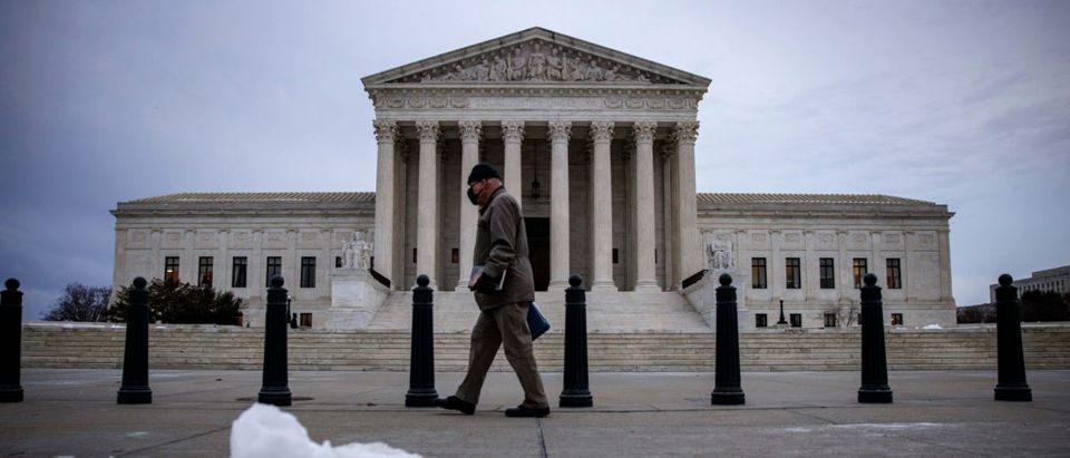 WASHINGTON, DC - JANUARY 07: A man walks past the U.S. Supreme Court following the first snow fall of winter on January 7, 2022 in Washington, DC. The Supreme Court is set to review Bidens private sector COVID vaccination rules. (Photo by Samuel Corum/Getty Images)