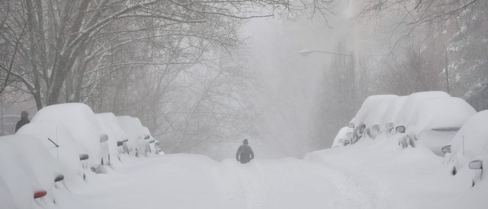 TOPSHOT - A pedestrian walks in the center of a snow-covered residential street in Washington, DC on January 23, 2016. A deadly blizzard with bone-chilling winds and potentially record-breaking snowfall slammed the eastern US on January 23, as officials urged millions in the storm's path to seek shelter -- warning the worst is yet to come. / AFP / MANDEL NGAN (Photo credit should read MANDEL NGAN/AFP via Getty Images)