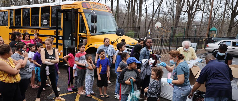 Dozens of families receive food distributed by Montgomery County Public Schools as part of a program to feed children while schools are closed due to the coronavirus March 20, 2020 in Silver Spring, Maryland. Millions of children across the country rely on meals they get at school, which are closed in an attempt to suppress transmission of the COVID-19 virus. (Photo by Chip Somodevilla/Getty Images)