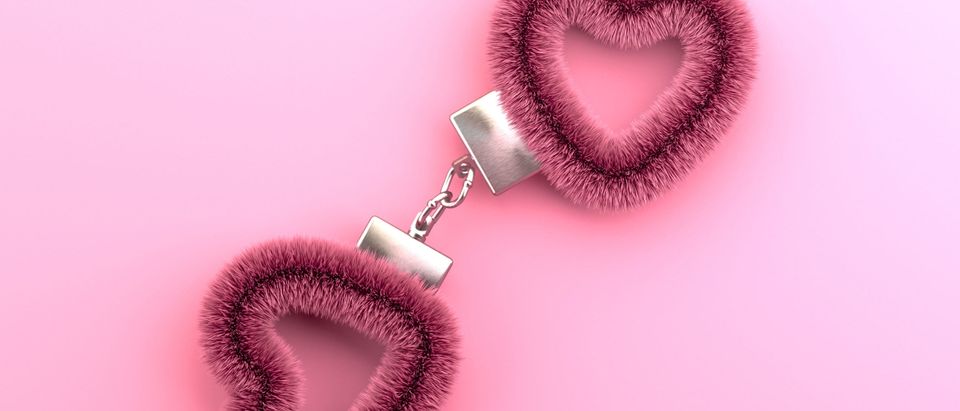 Heart shaped pink fuzzy handcuffs [Shutterstock/Nadin Panina]