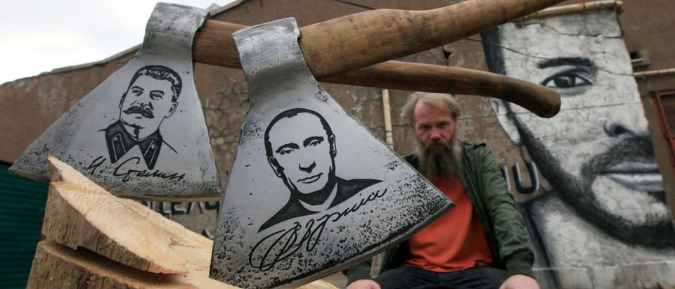 Russian artist Vasily Slonov poses for a picture with axes engraved with portraits of Russian President Vladimir Putin and Soviet leader Josef Stalin in Krasnoyarsk