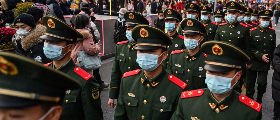 Chinese paramilitary policemen walk on a street while people visiting Yu Garden during the celebration of the Lantern Festival which marks the end of Lunar New Year celebrations, in Shanghai, on February 15, 2022. (Photo by Hector RETAMAL / AFP) (Photo by HECTOR RETAMAL/AFP via Getty Images)