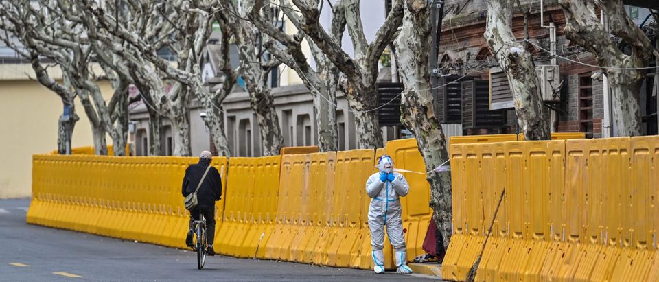 TOPSHOT - A worker, wearing a protective gear, stands next to barriers during lockdown as a measure against the Covid-19 coronavirus in Jing'an district, in Shanghai on March 31, 2022. (Photo by Hector RETAMAL / AFP) (Photo by HECTOR RETAMAL/AFP via Getty Images)