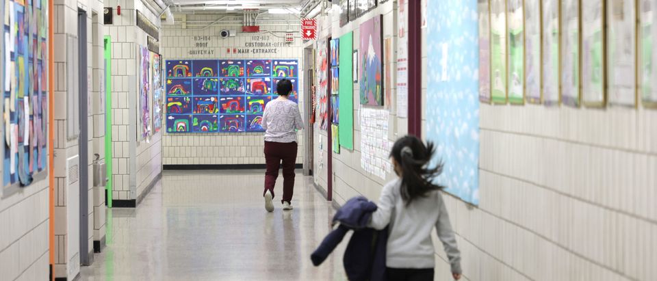 Principal Alice Hom walks a hallway followed by a student at Yung Wing School P.S. 124 on on April 11, 2022 in New York City. (Photo by Michael Loccisano/Getty Images)