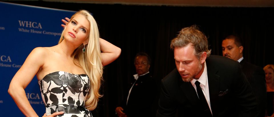 Actress Jessica Simpson is helped with her dress by Eric Johnson as they arrive on the red carpet at the annual White House Correspondents' Association Dinner in Washington