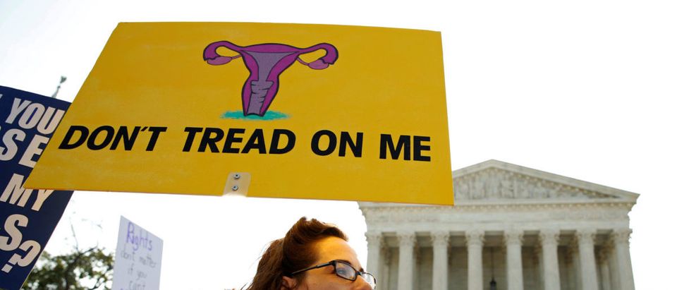 Demonstrators hold signs outside the U.S. Supreme Court in Washington